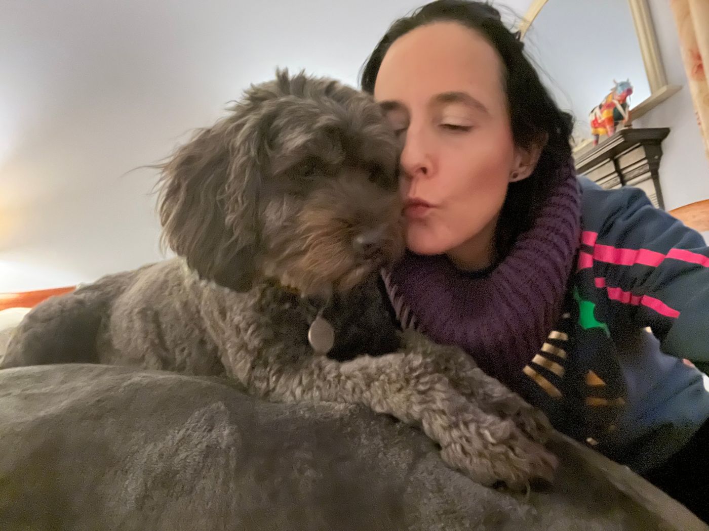 Hilary kissing a grey curly haired dog